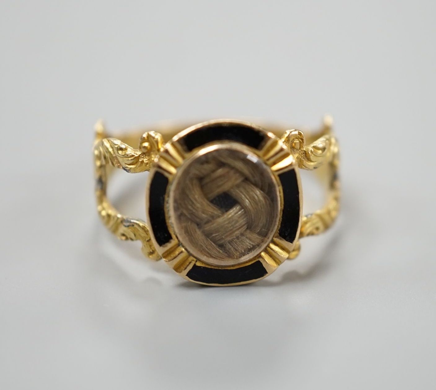 A George IV 18ct gold, black enamel and plaited hair set mourning ring, with engraved monogram, size M, gross weight 3.3 grams (a.f.).